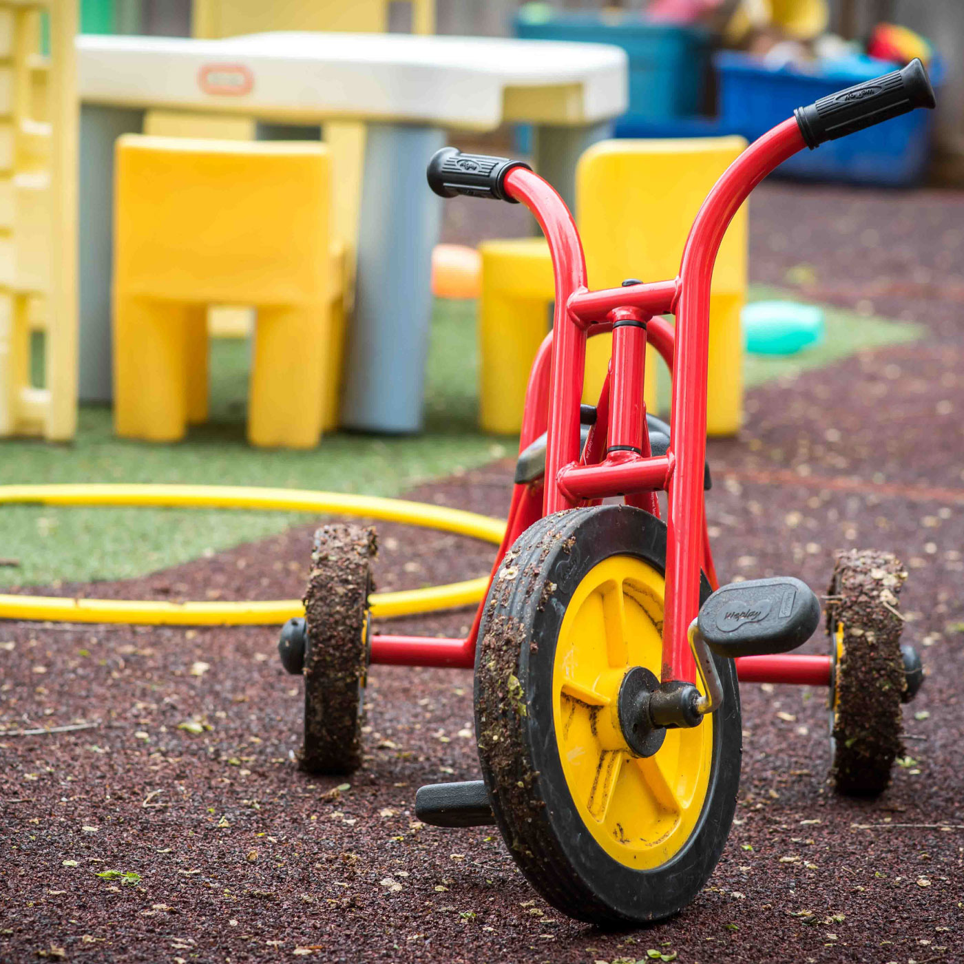 A red tricycle with yellow wheels on a playground