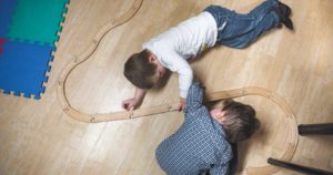 An areal shot of two young boys building a wooden train track