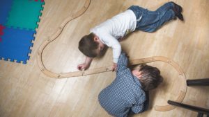An areal shot of two young boys building a wooden train track
