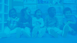 Five children sitting on the floor, laughing, and being silly. There is a blue overlay.